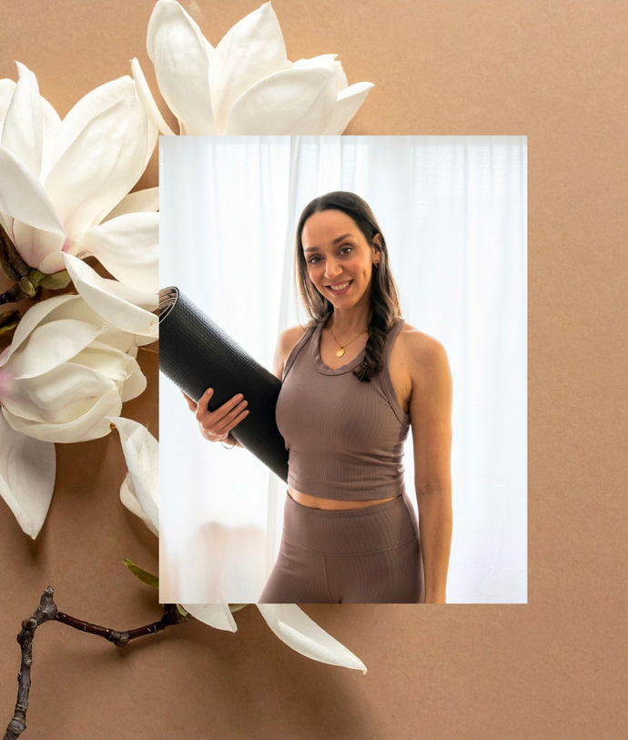 Woman in a brown athletic outfit smiling while holding a rolled yoga mat in front of a light curtain backdrop; collage-style floral background.